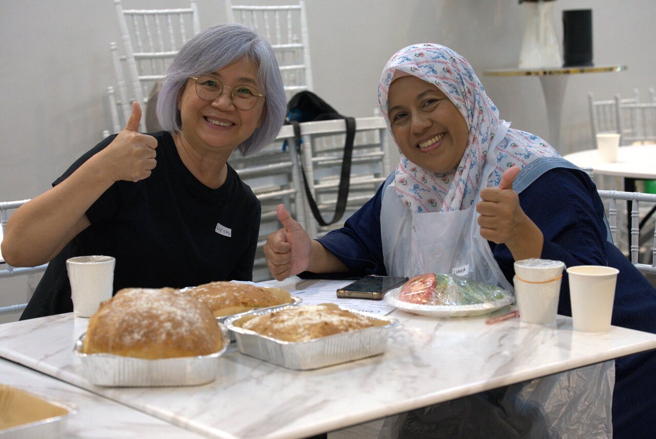 Two participants holding up their freshly baked ciabatta loaves at the Master Artist ciabatta bread workshop