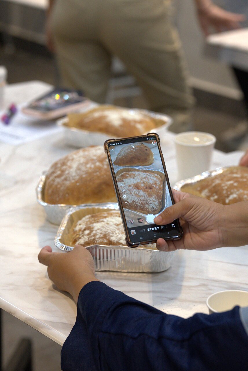A participant photographing the finished ciabatta loaves on their phone