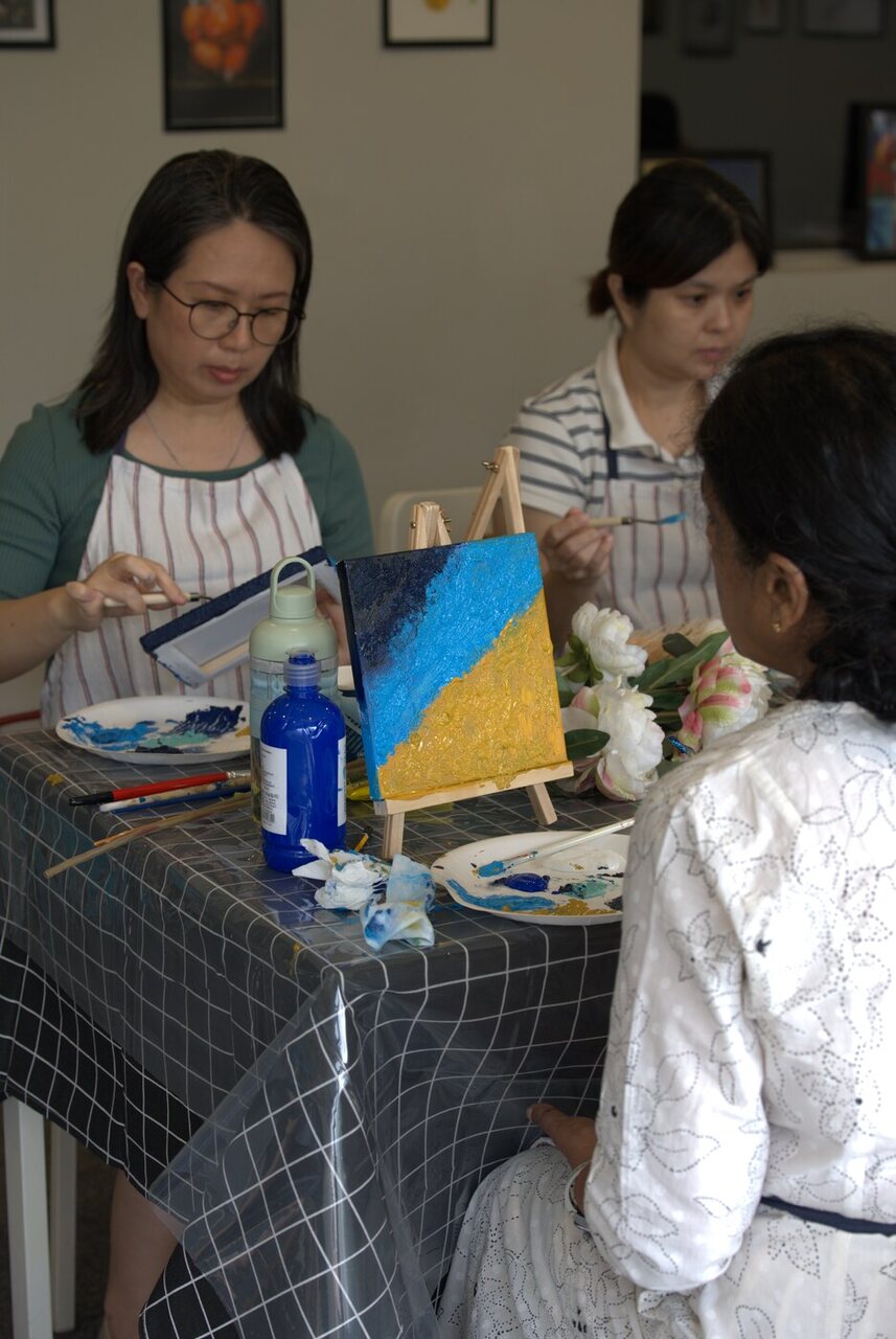 Twelve painters working on textured shoreline canvases at the Master Artist Golden Shores workshop