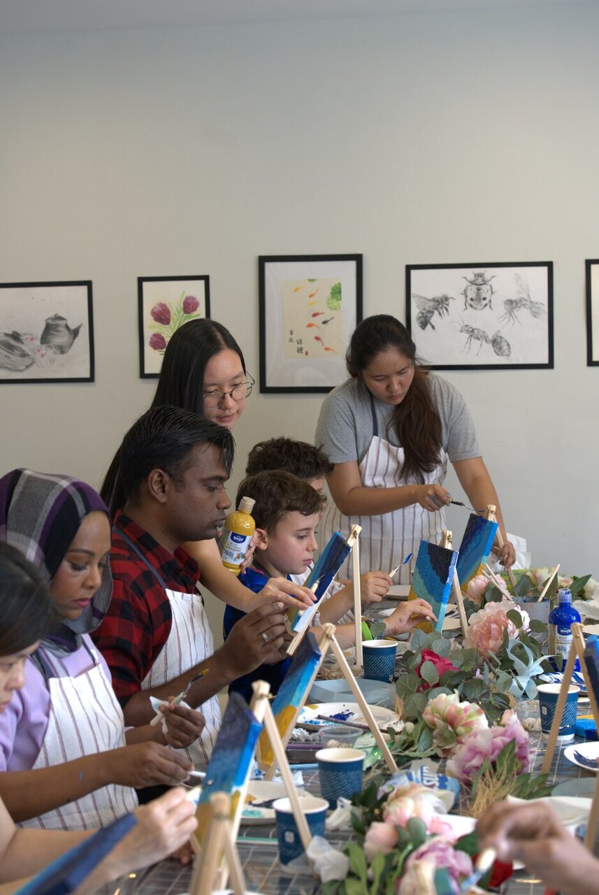 A teacher demonstrating the layered blue and gold canvas technique at the Golden Shores workshop
