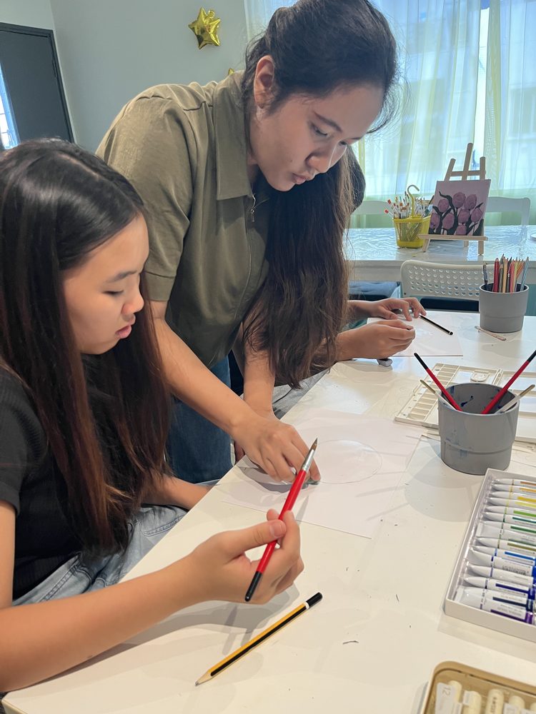 A teacher guiding a student through a watercolour painting